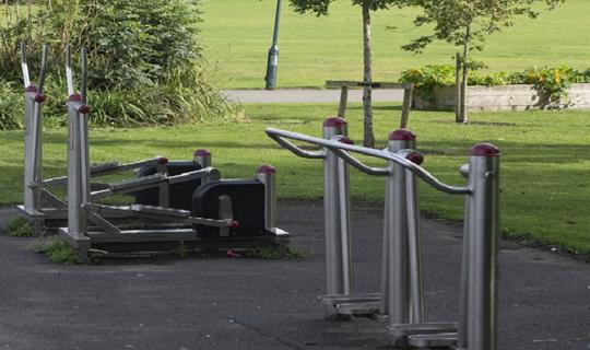 Gym equipment by grass and trees.