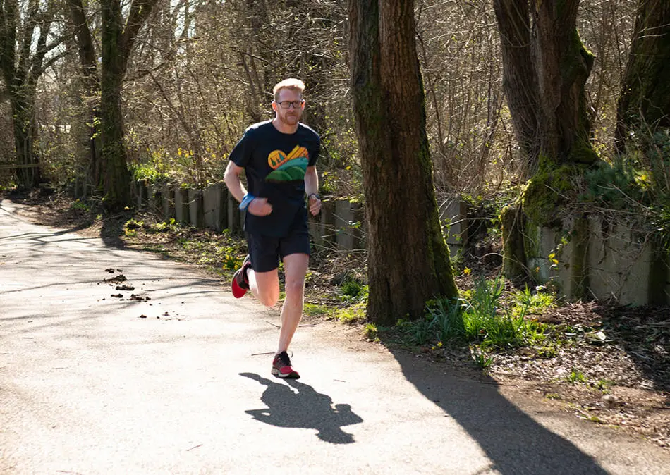 Man running on a countryside lane surrounded by trees