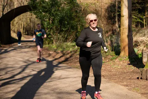 Person running on a countryside lane surrounded by trees