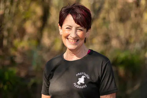Smiling person wearing a black t-shirt with trees in the background