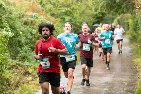 A group of runners on a countryside lane surrounded by trees