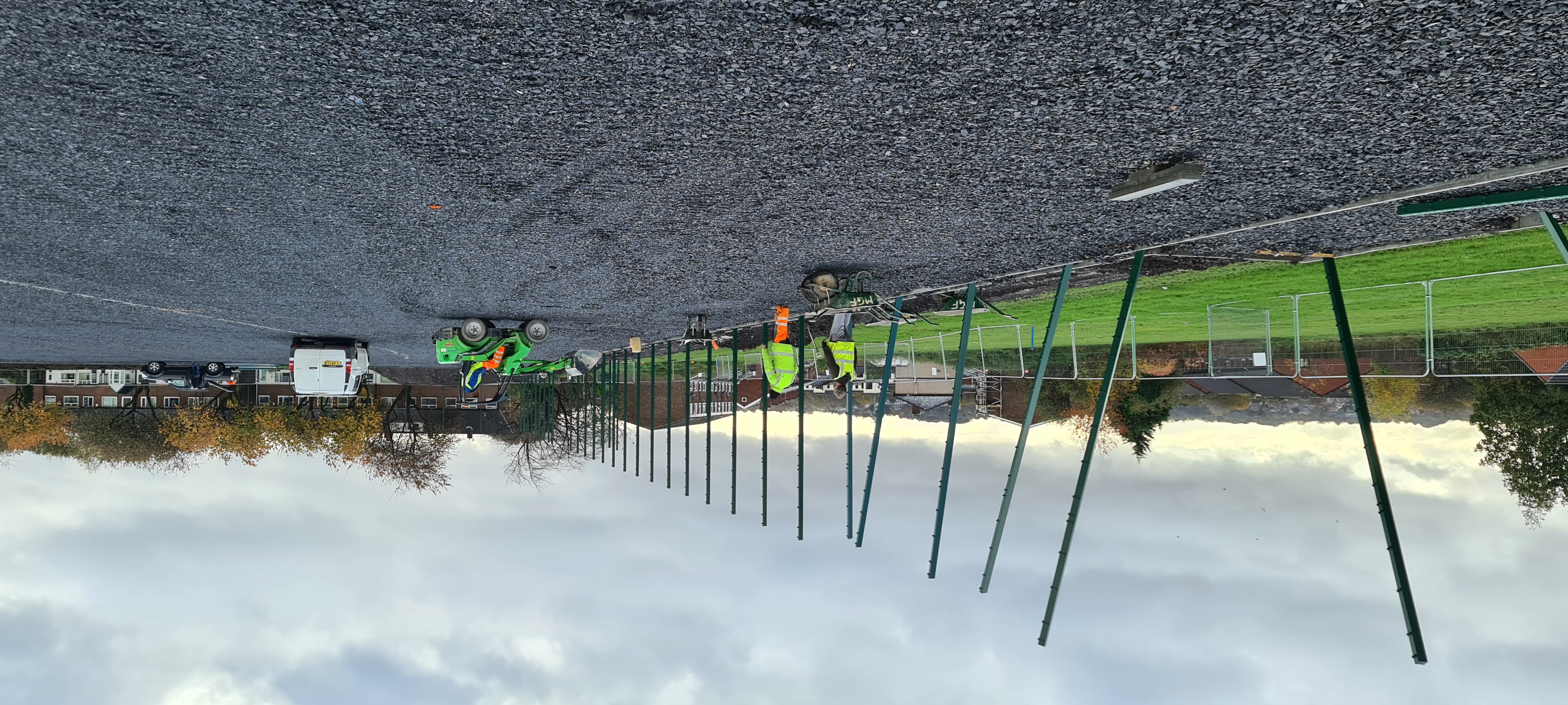 People in high-viz clothes erecting a high fence on a playing field