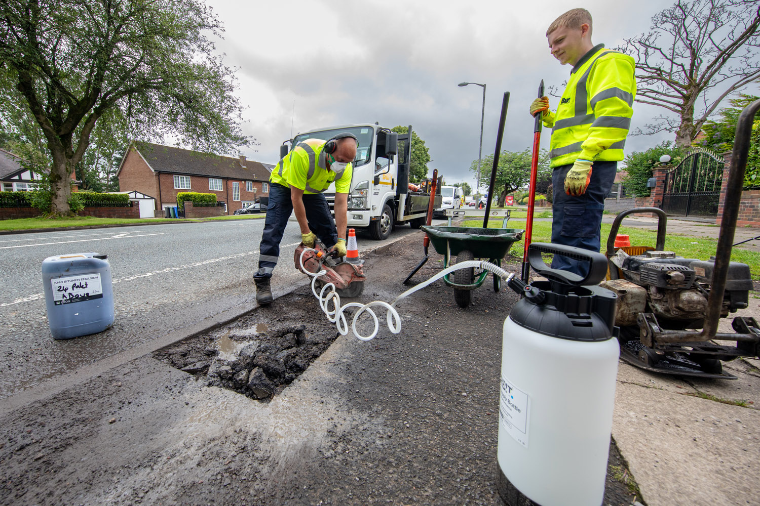 A person using a handheld machine to cut into a road surface