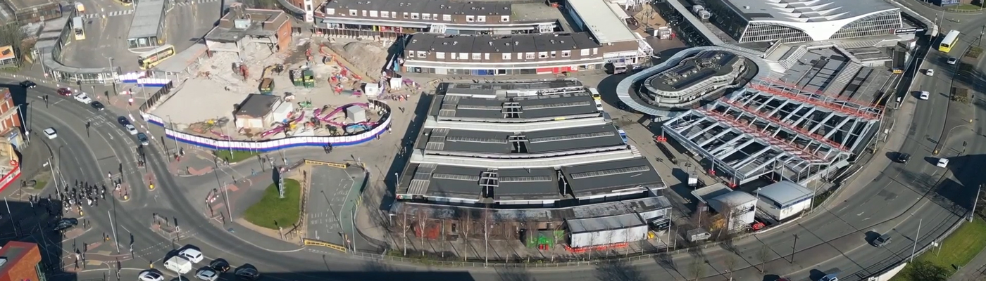 Aerial view of a construction site and large buildings surrounded by a road