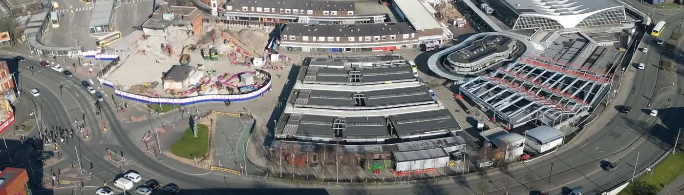 Aerial view of a construction site and large buildings surrounded by a road