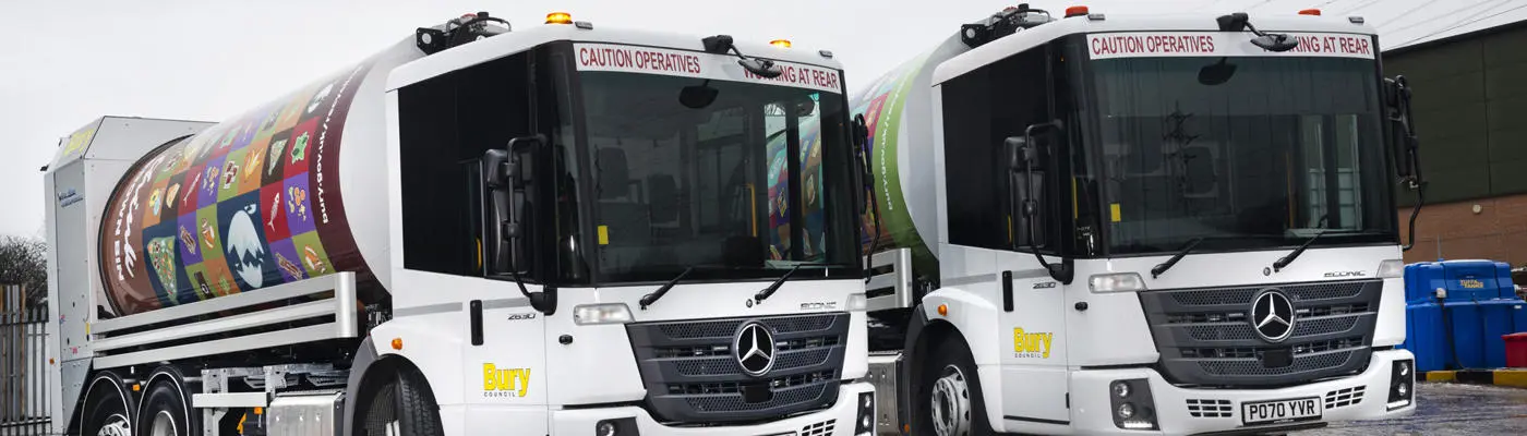 Two bin collection vehicles parked up in a service yard