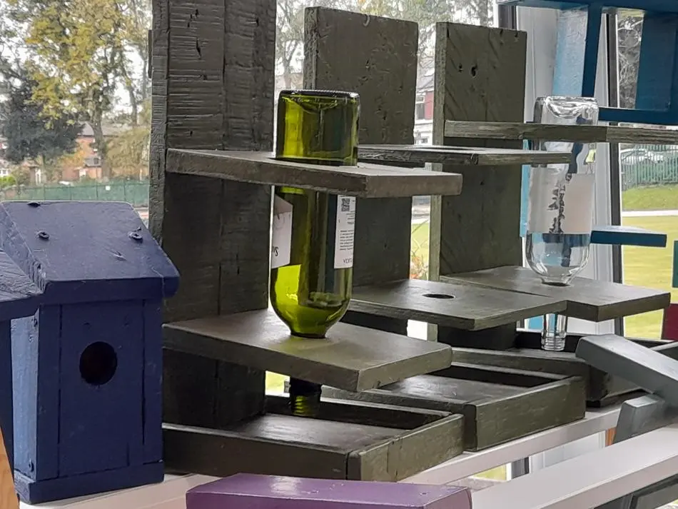 Upside down empty wine bottle in a wooden stand.