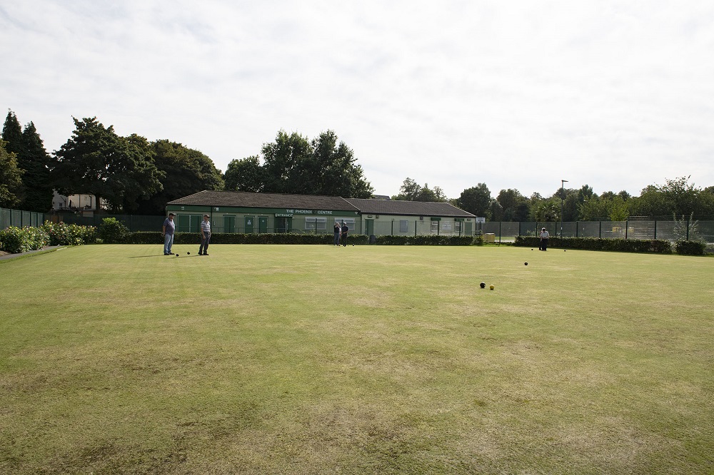 Bowlers bowling on green by club house.