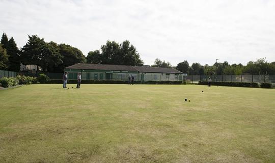 Bowlers bowling on green by club house.
