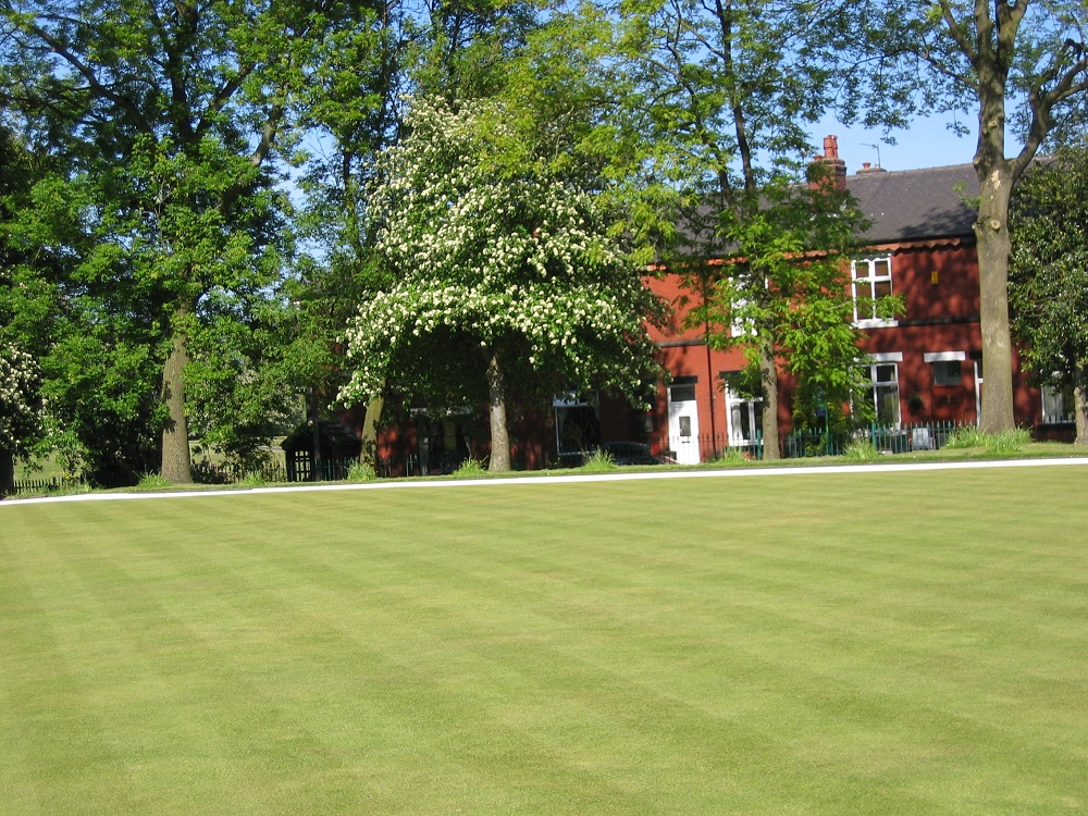 Bowling green by trees and houses.