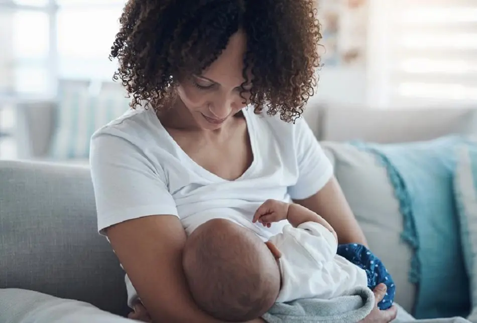 A baby being cradled whilst being breastfed.