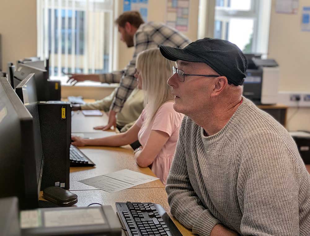 A row of people sat at computers