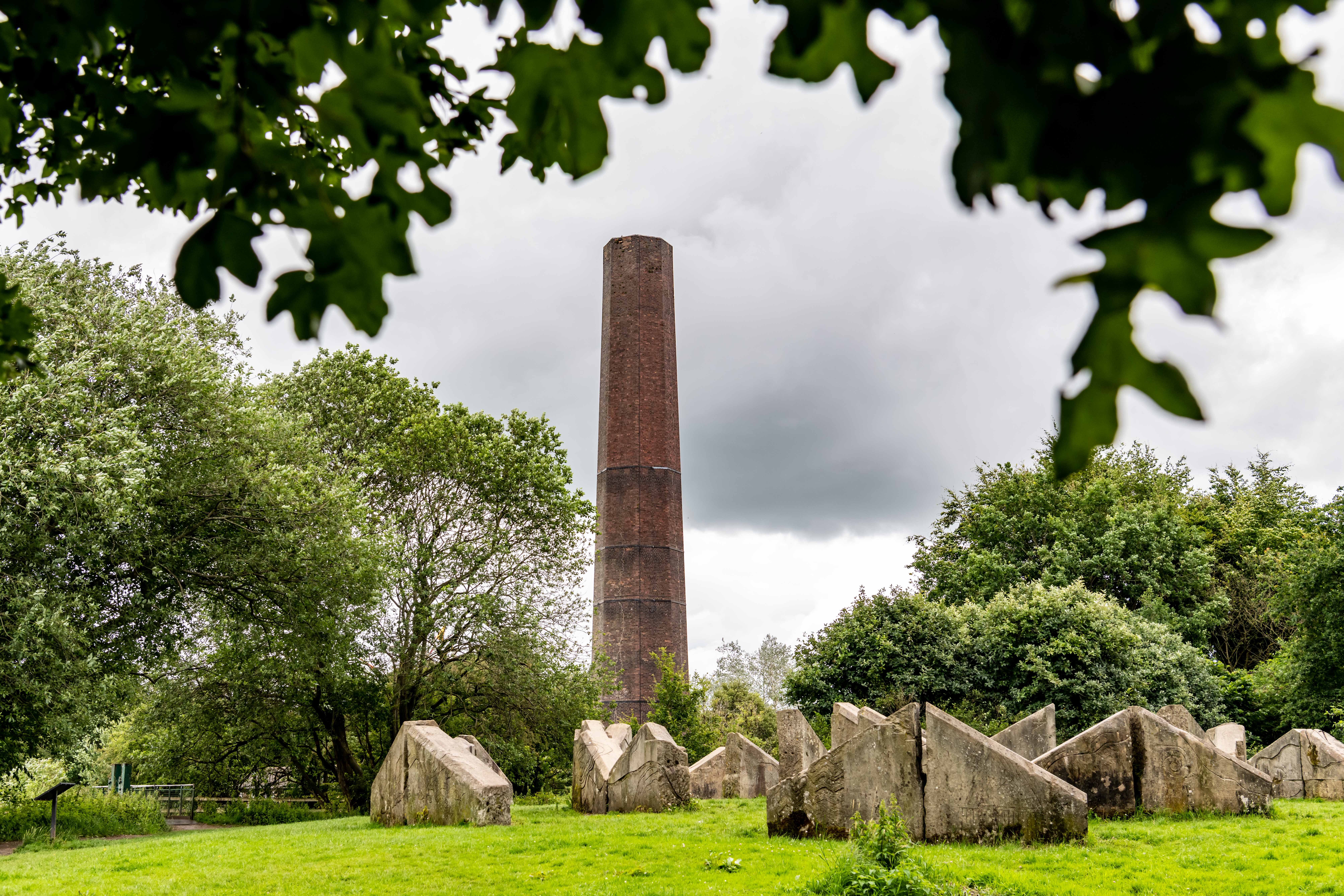 A large stone chimney surrounded by large stones in a park
