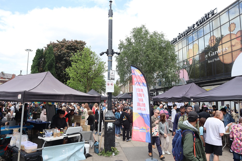 Lots of people standing around food stalls.