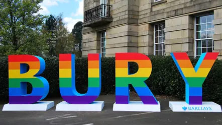 Letters spelling out Bury, coloured with the Pride rainbow design