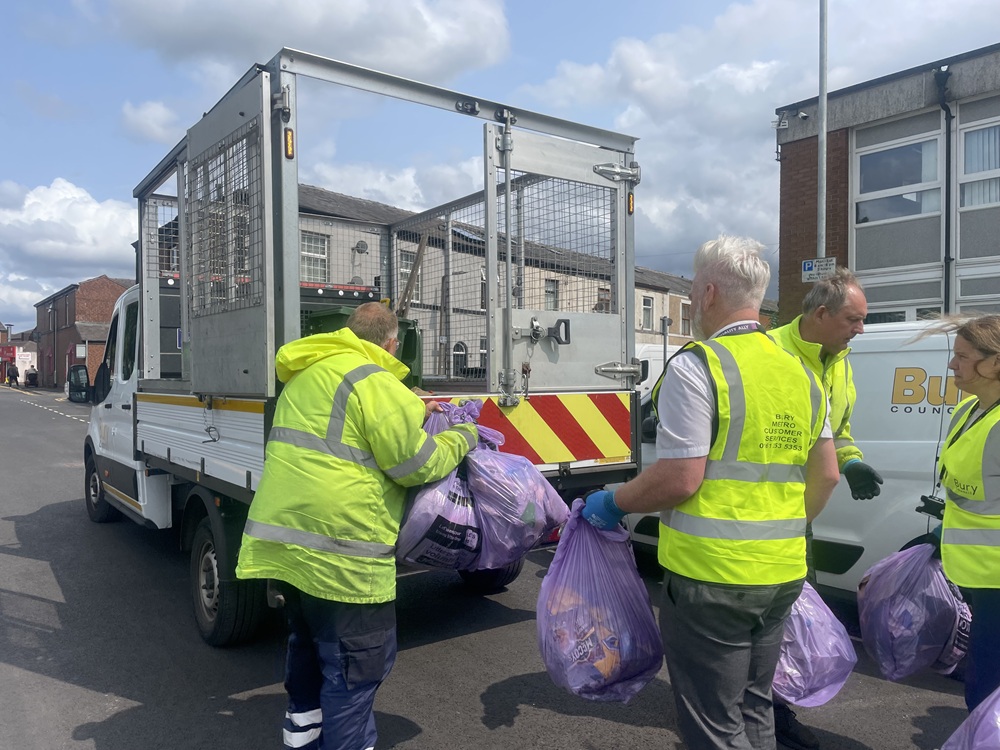 People putting rubbish bags into a van