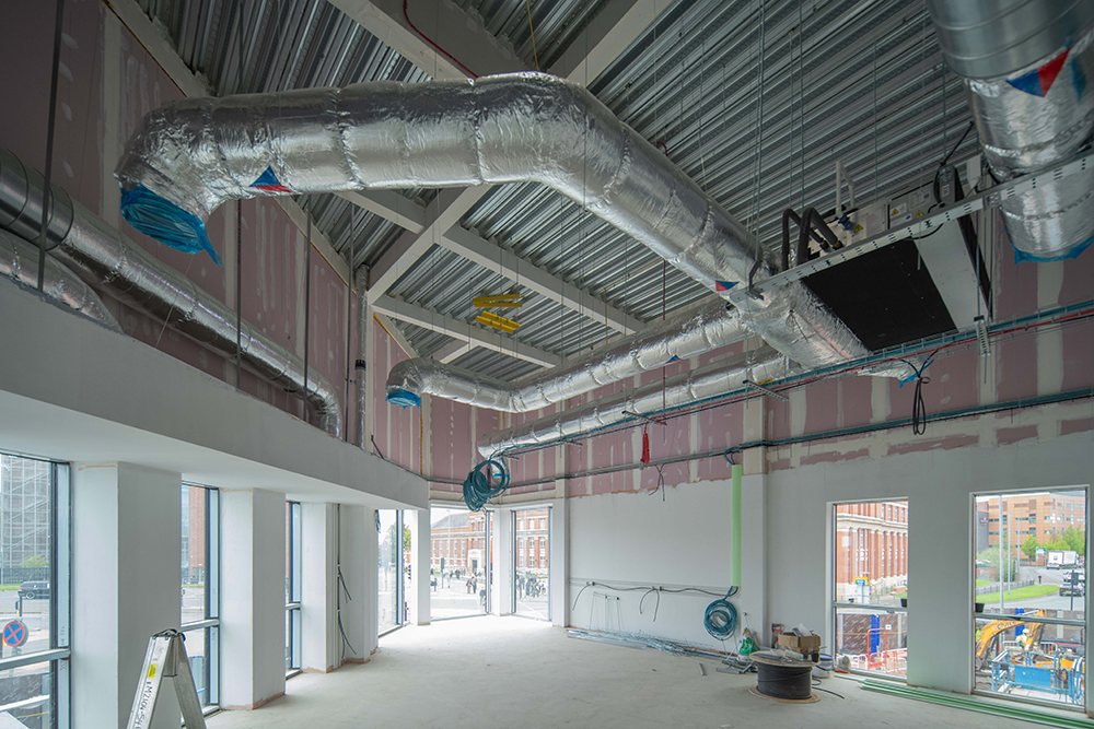 A large empty room with windows and exposed pipework in the ceiling