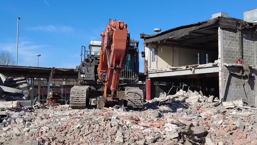 Large digger on a building site next to a vacant building