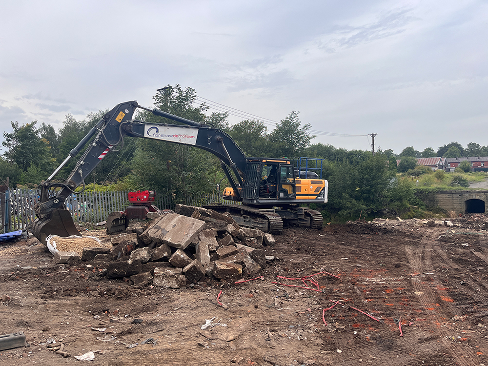 A heavy construction vehicle with a claw attachment next to a pile of rubble