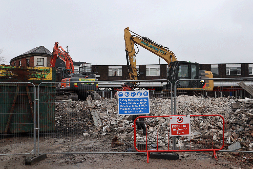 A large digger on a building site covered in rubble