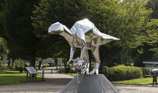 Metal dinosaur sculpture on plinth.