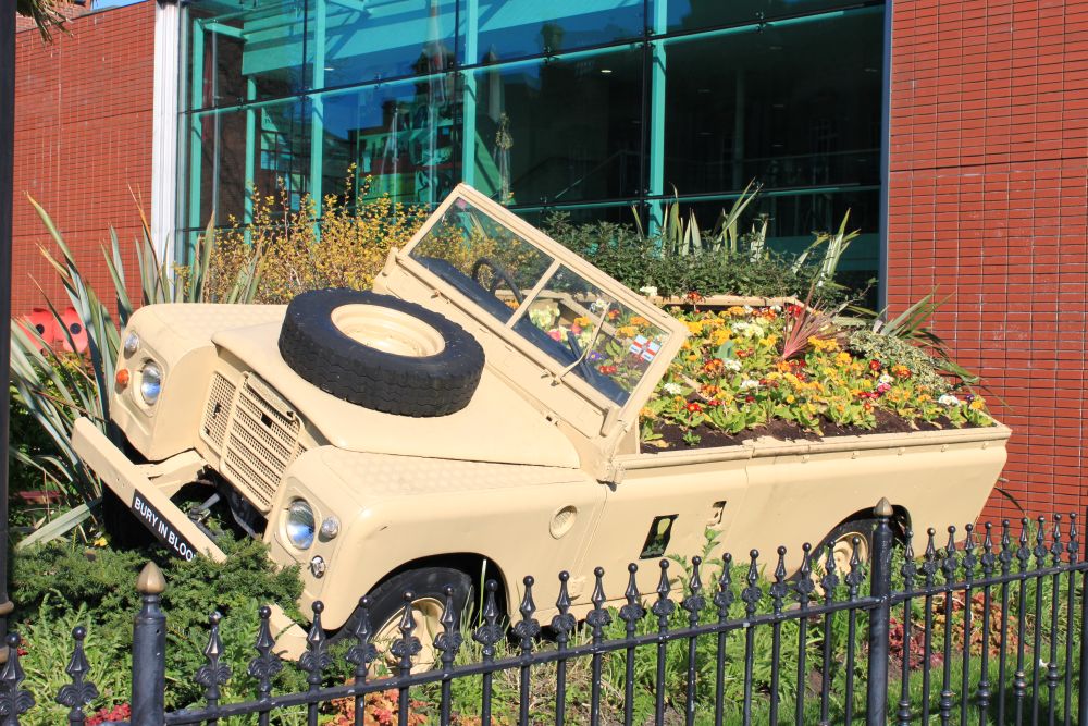 A Land Rover car filled with flowers as part of a gardening display.