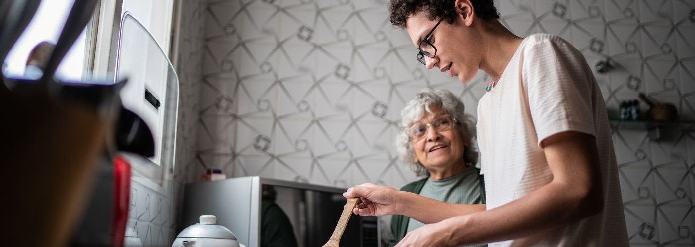 A young person helping an older person with cooking
