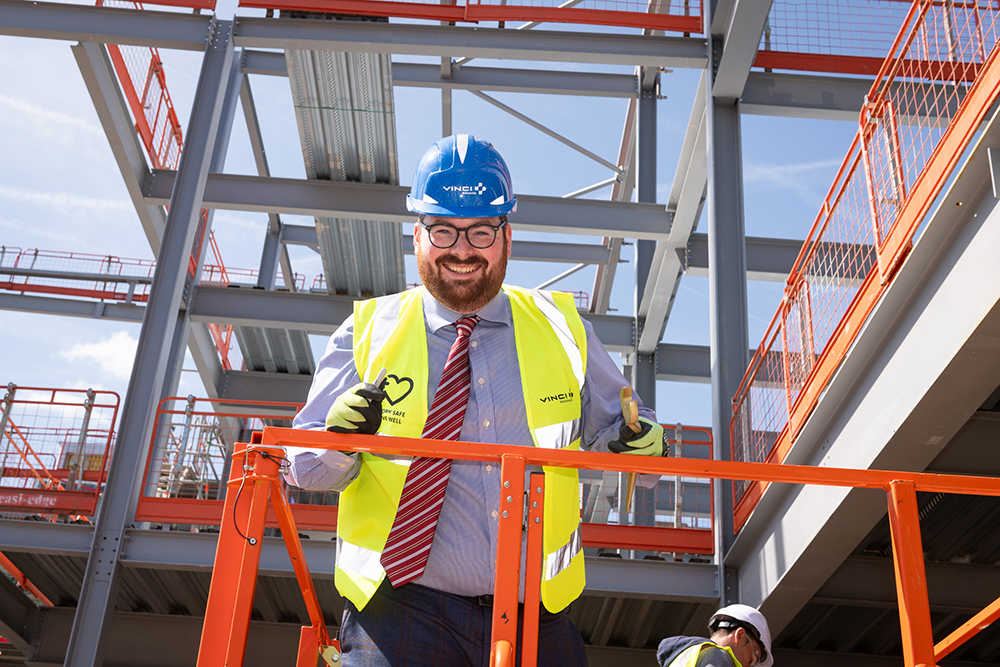 A person wearing protective clothing holding a spanner who is high up in a building on a construction site