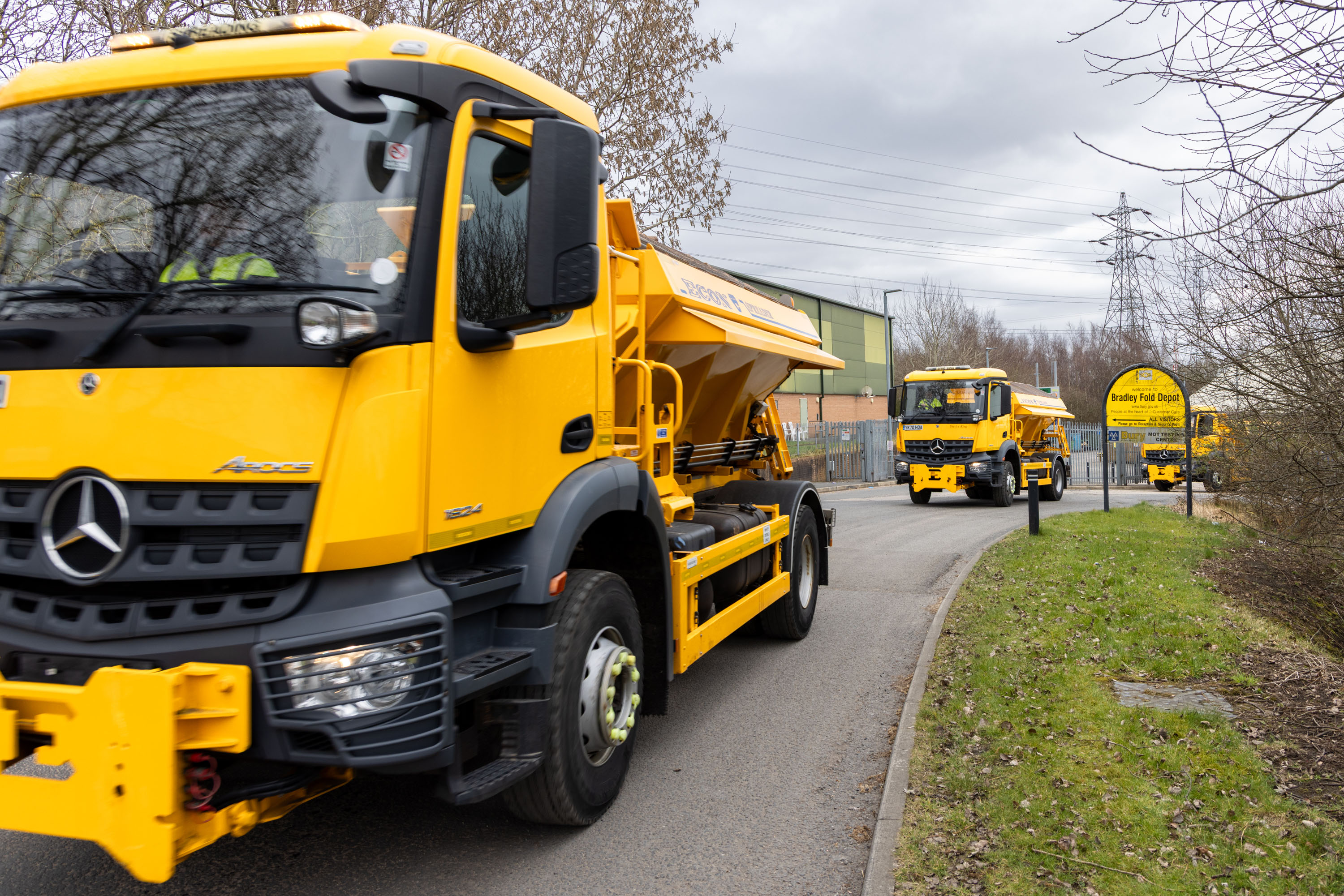 Two large yellow vehicles travelling along a road