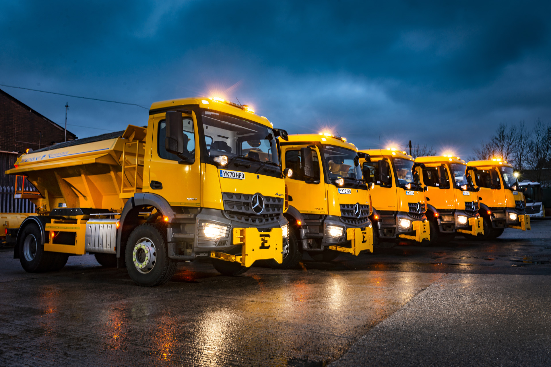 Five large yellow vehicles lined up next to each other