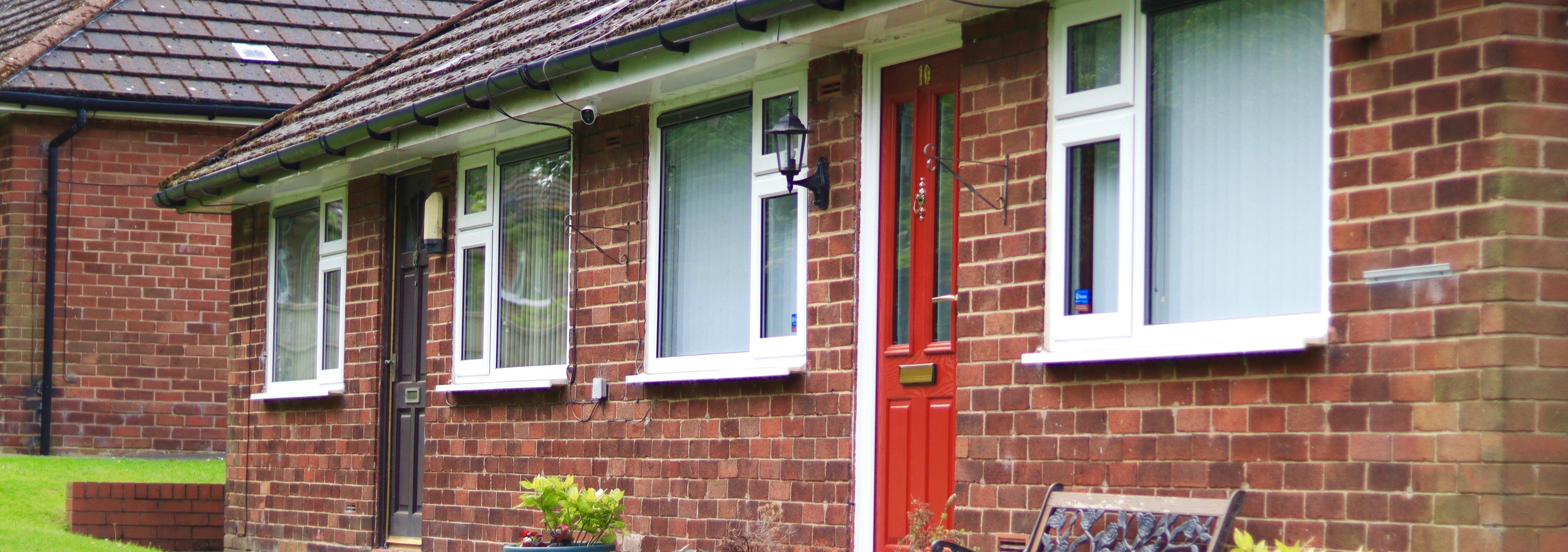 The front of two one-storey houses. Each house has one door and two windows.