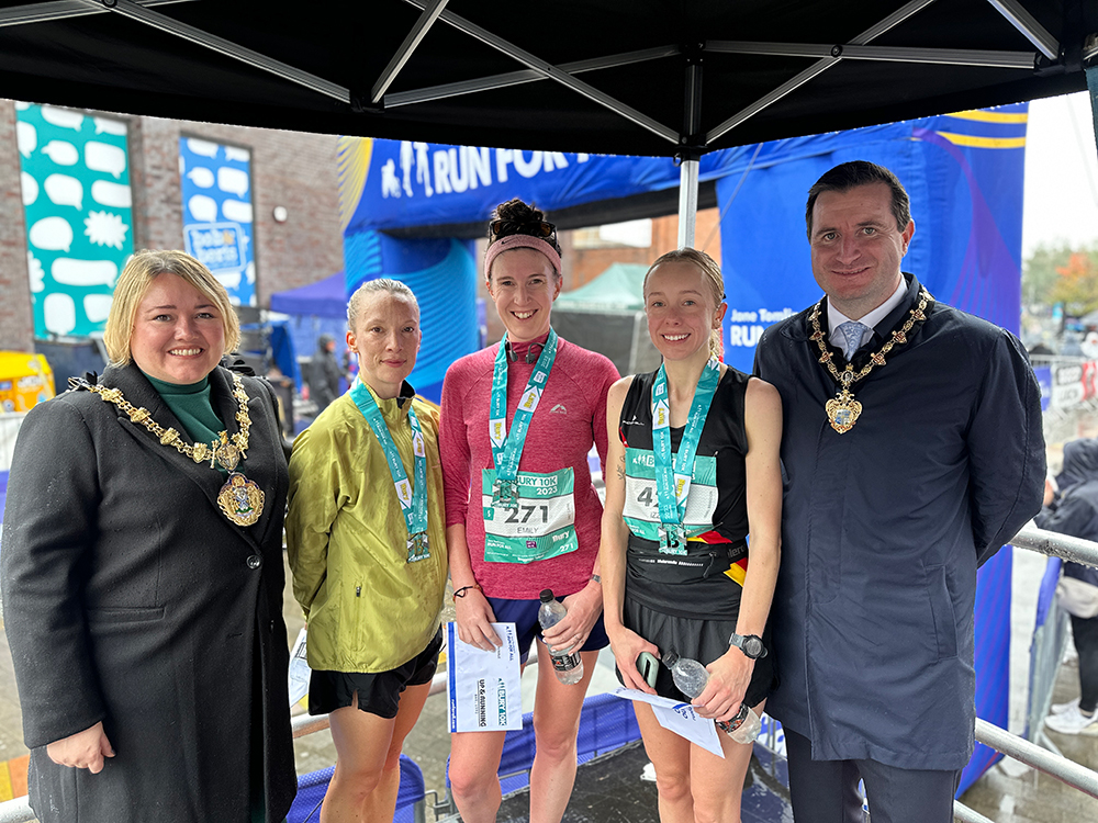 Three people wearing winner medals around their necks and two people wearing gold ceremonial chains