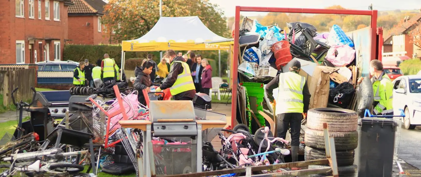 staff and tenants stood by a full skip of rubbish