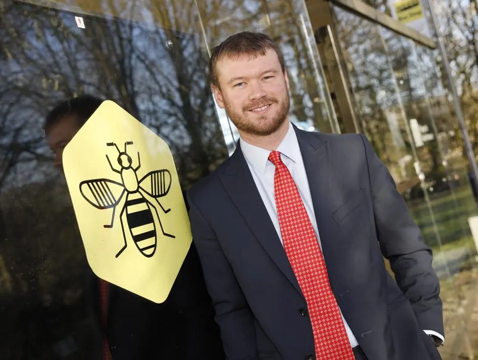 A person leaning against a bus shelter next to a drawing of a bee inside a hexagon shape