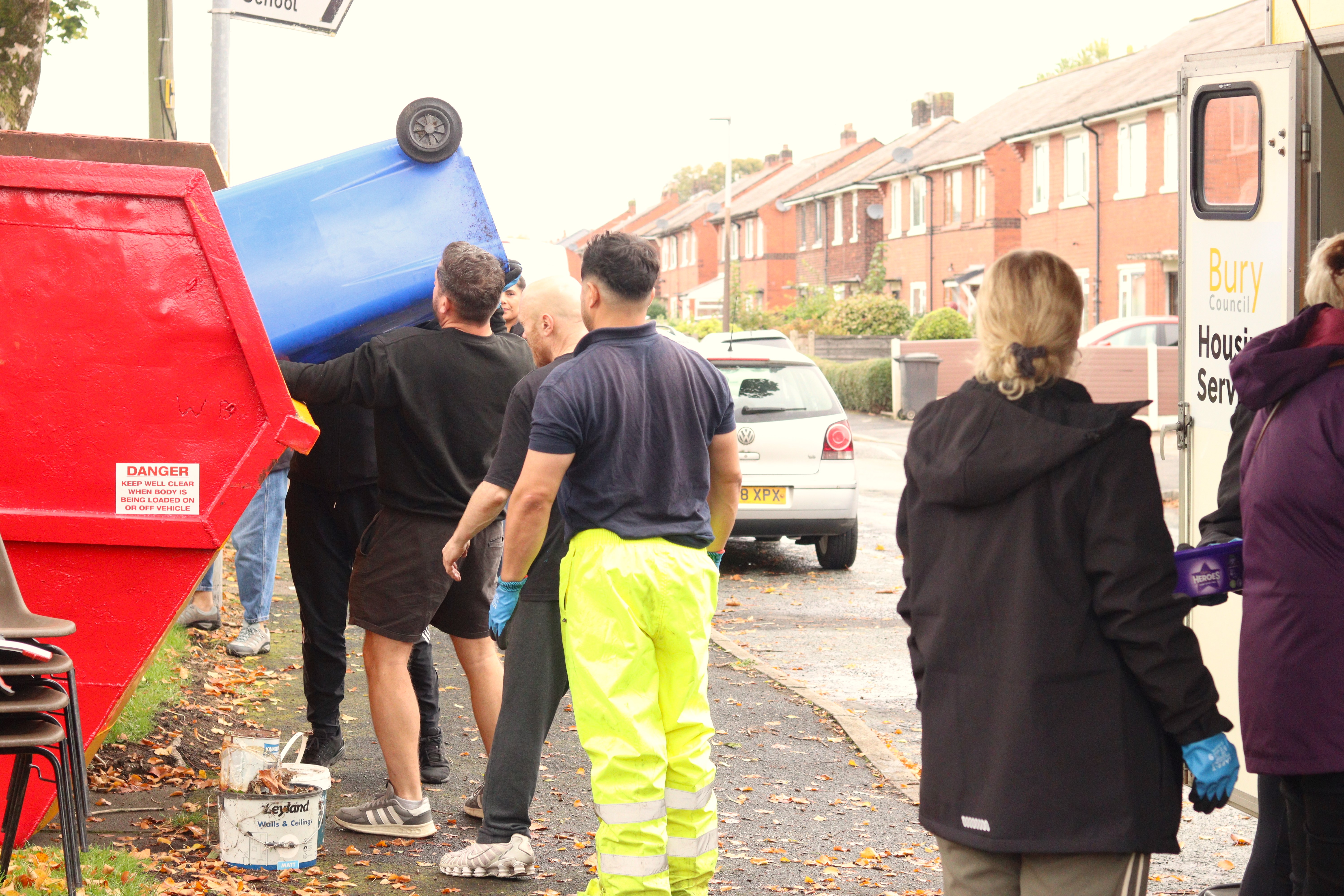 staff emptying bin into skip