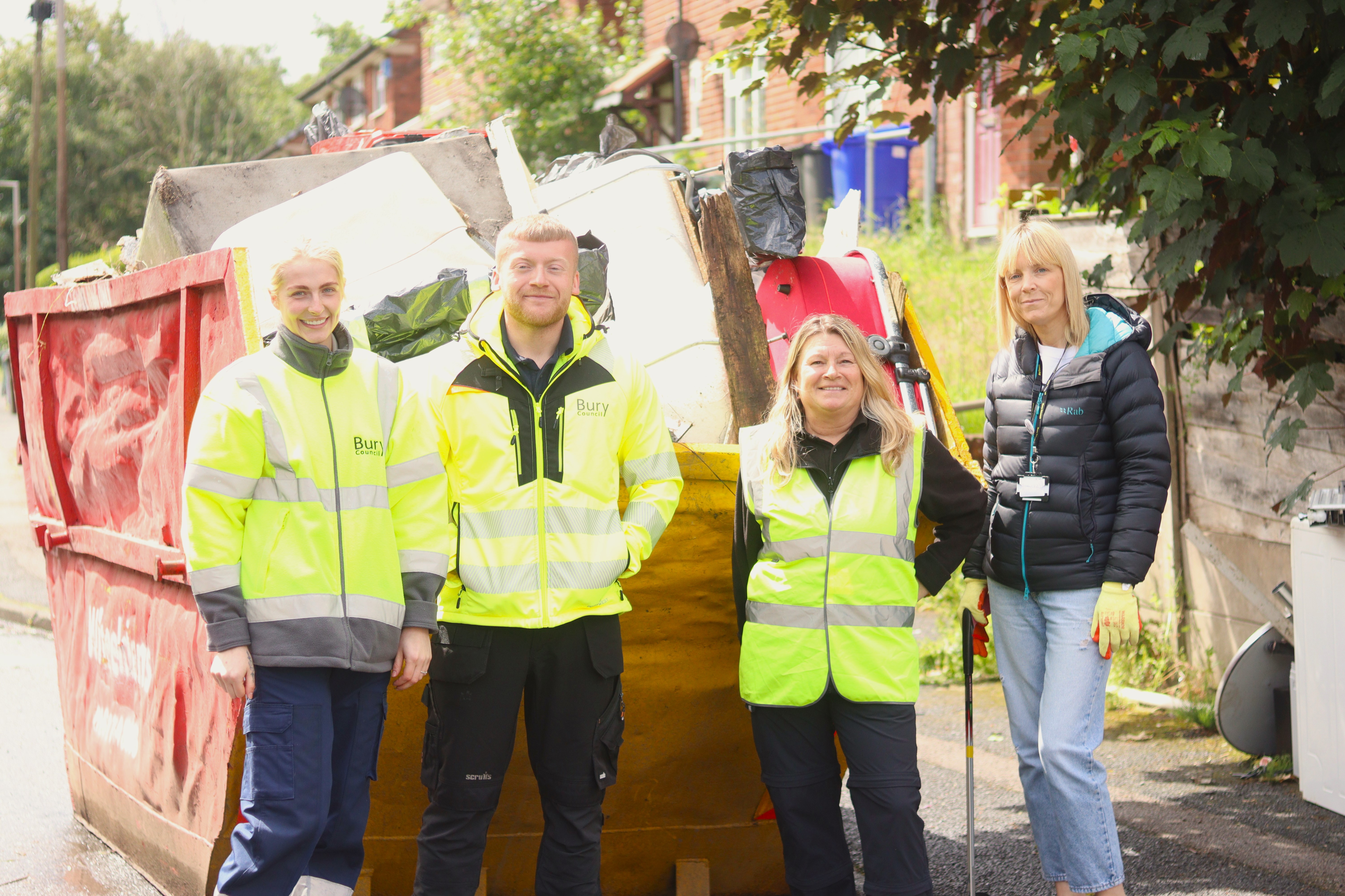 Housing staff stood in front of a full skip