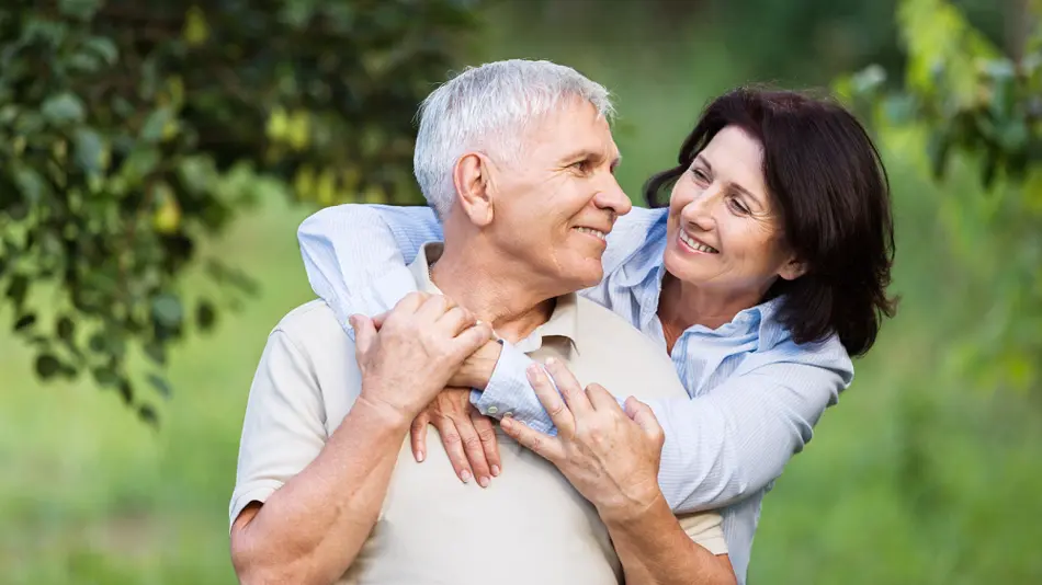 Two people with their arms round each other smiling.