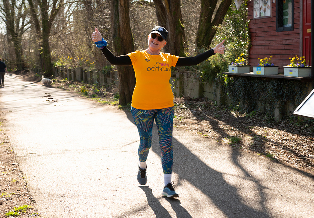 Person running on a countryside lane surrounded by trees