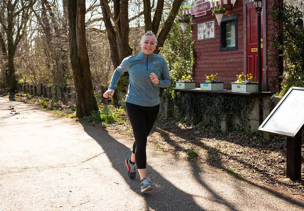 Person running on a countryside lane surrounded by trees