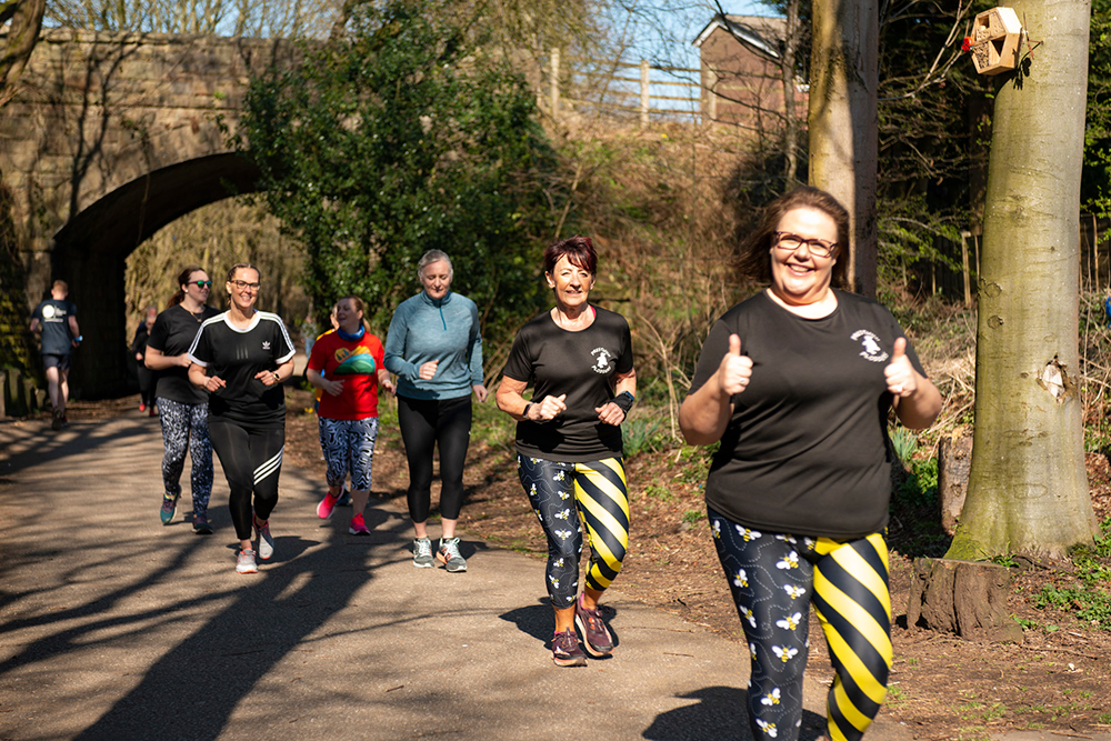 Group of people running on a countryside lane surrounded by trees