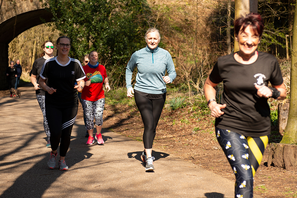 Group of people running on a countryside lane surrounded by trees