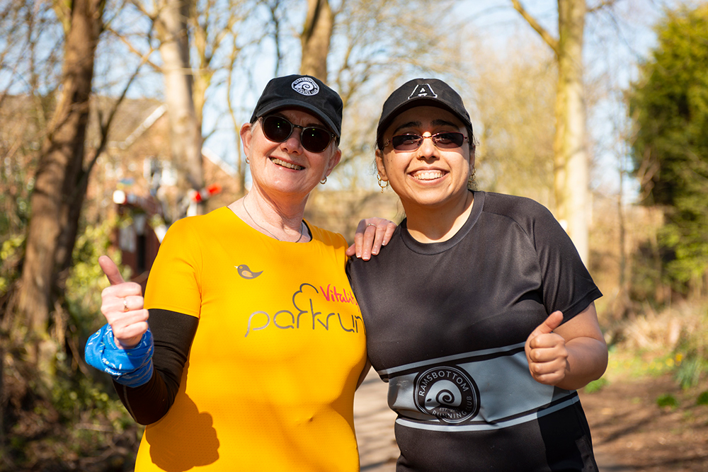 Two smiling people giving the thumbs up signal, dressed in sportswear