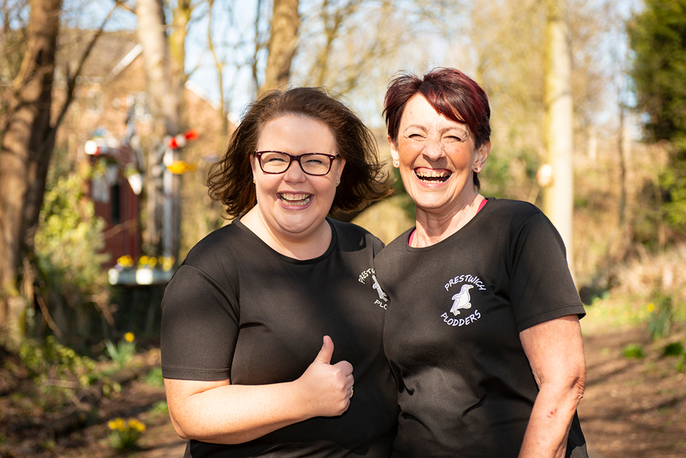 Two smiling people giving the thumbs up signal, dressed in sportswear