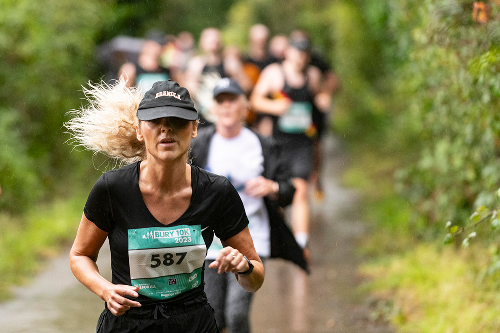 A group of runners on a countryside lane surrounded by trees