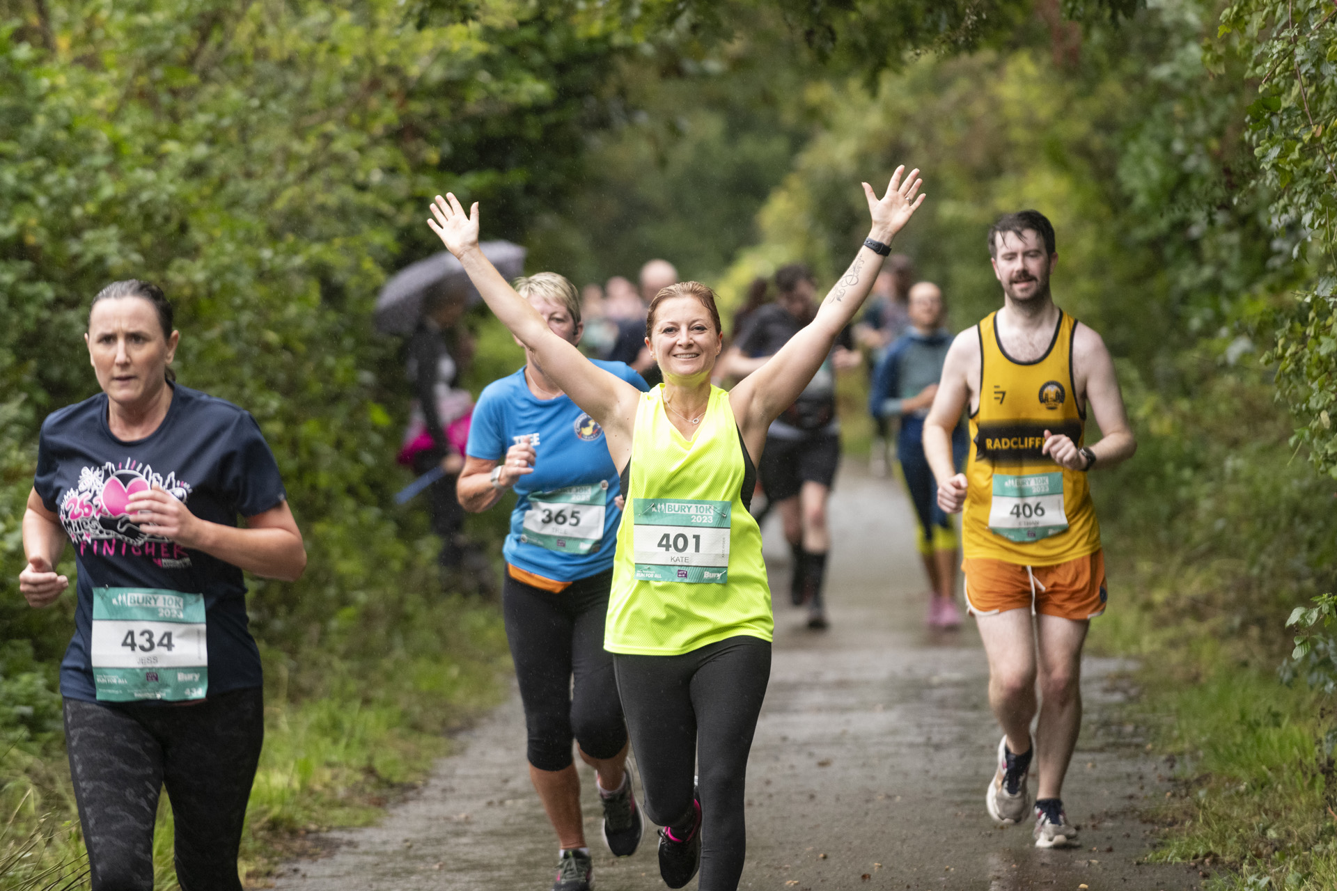 A group of runners on a countryside lane surrounded by trees