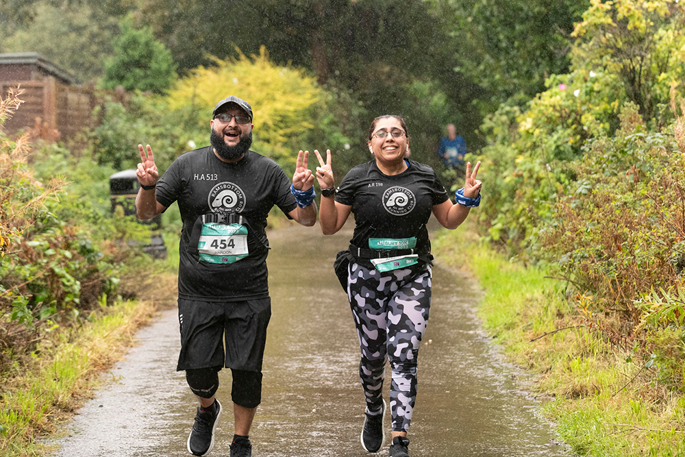 Two people running side by side on a countryside lane