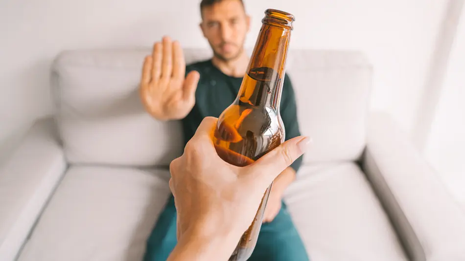 Person refusing a bottle of beer.