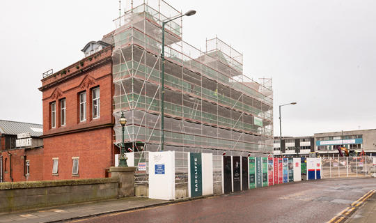 A red brick building with scaffolding covering one wall