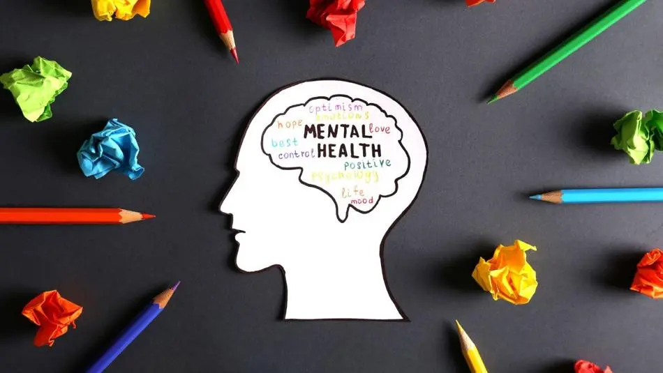 Drawing of a brain with words connected to mental health surrounded by pencils