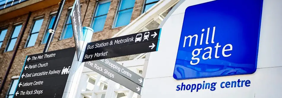 A blue and white sign on the front of a building that says Mill Gate shopping centre